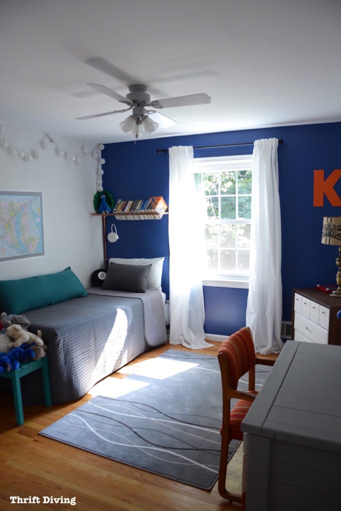 Tween Boys Blue Bedroom Makeover - Deep blue bedroom using Behr Mosaic Blue, IKEA curtains and bedding, and a copper piping bookshelf. Other walls are painted an off-white gray. | Thrift Diving