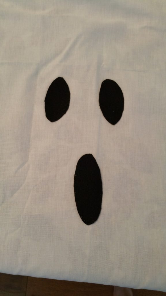How to Make Halloween Ghost Lights For Your Front Porch - Use spray adhesive to attach black felt eyes and mouth on white sheet. - Thrift Diving