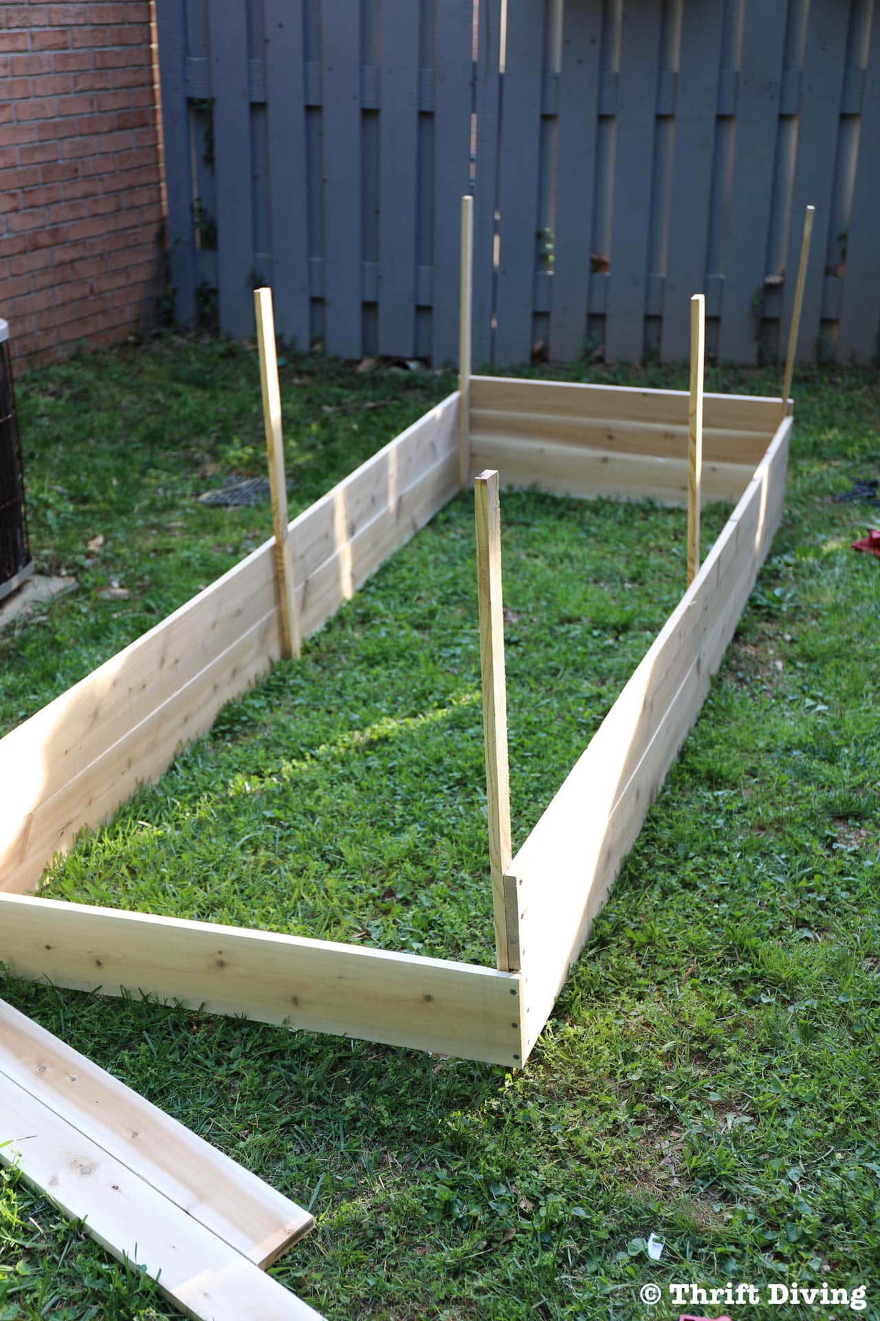 How to Build a Raised Garden Bed From Scratch - Add wooden stakes. - Thrift Diving