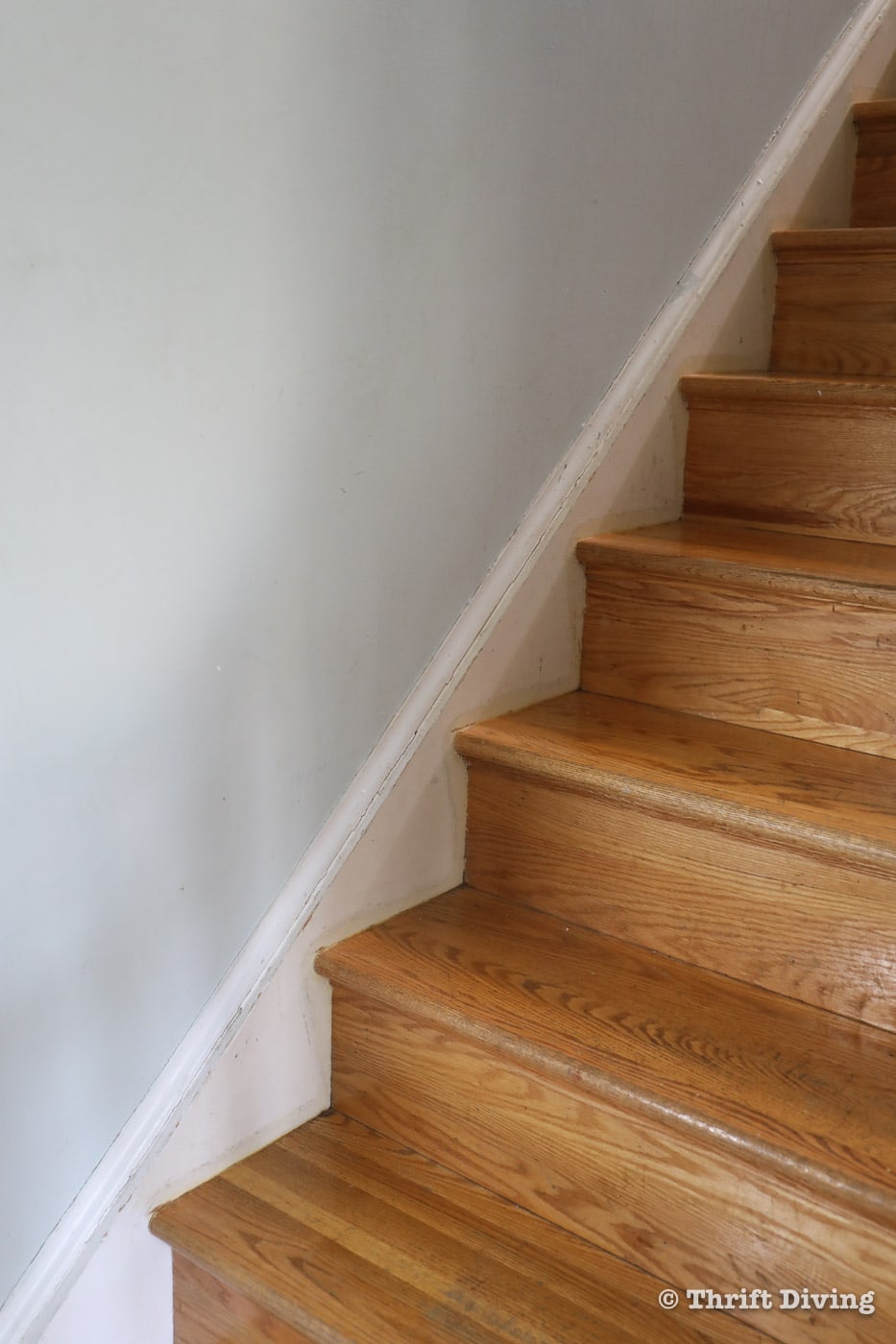 Worn oak stairs need to be refinished, but sanding and restaining stairs is a big job. Try painting the stairs and install a stair runner. Here's how (includes VIDEO tutorial). - Thrift Diving