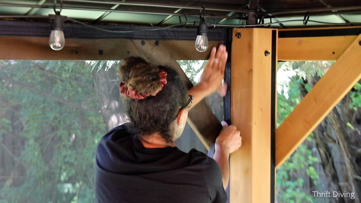 How to Make DIY Gazebo Screens - Hanging gazebo screens with Velcro inside of a wooden gazebo.
