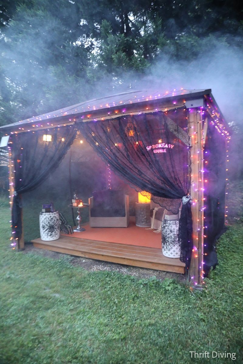 Spooky outdoor gazebo decorated for Halloween, with fog, lights, and fabric.