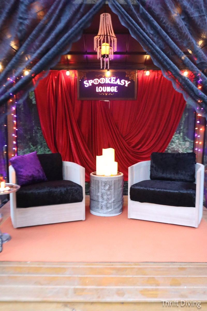 Gorgeously decorated gazebo with black lace curtains, red velvet, and a chandelier in the gazebo.