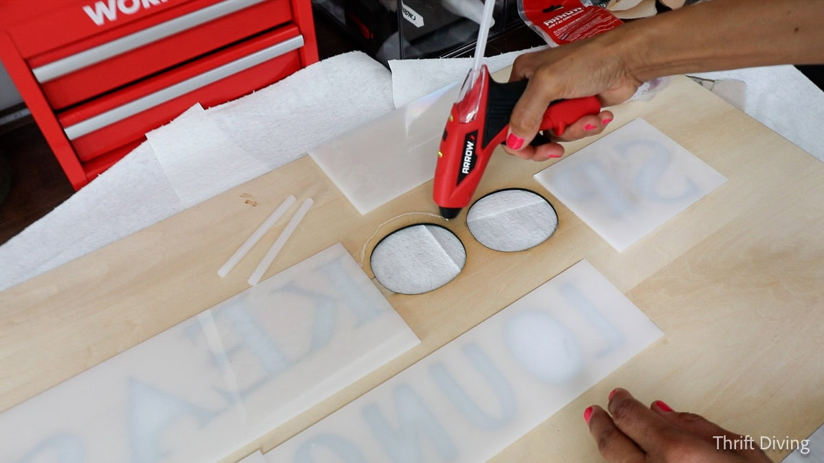 Using a glue gun to attach frosted acrylic to custom laser engraved light-up sign.