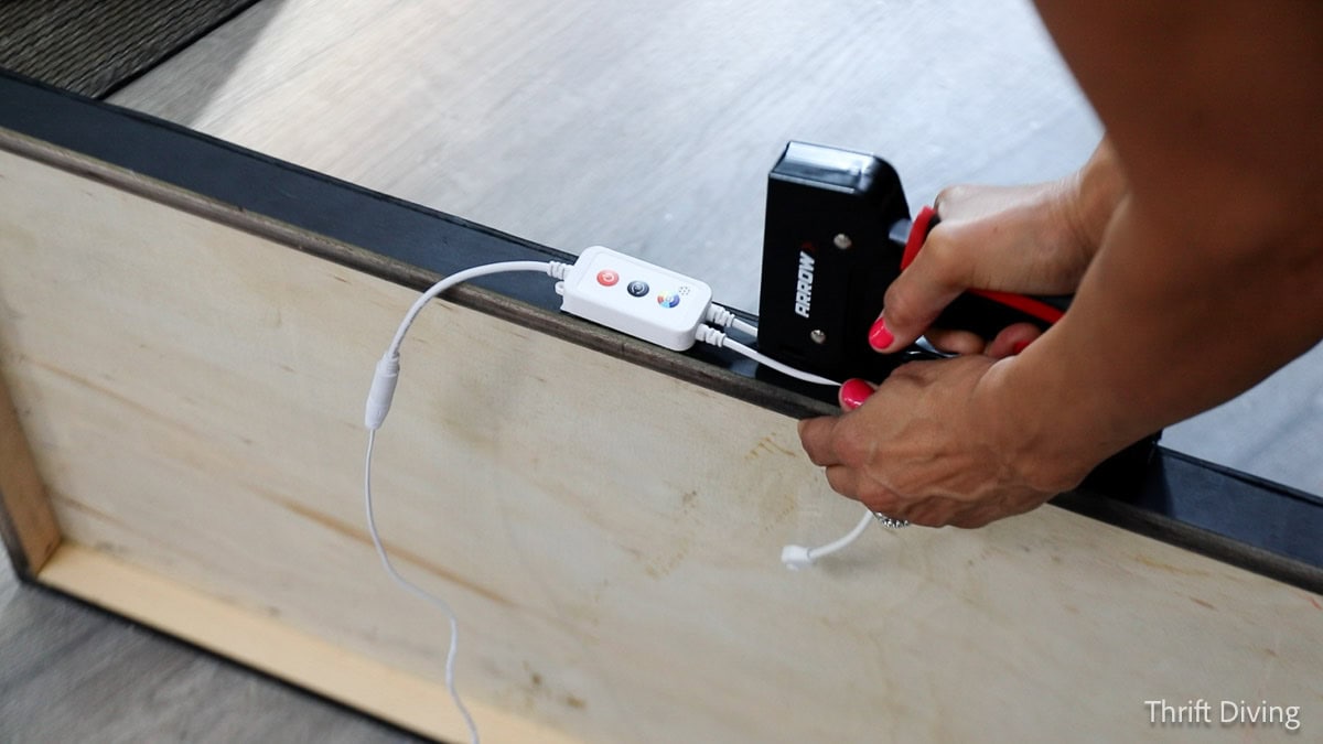 Stapling wires to wooden light-up sign frame.