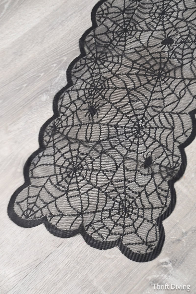 Dollar Tree lace Halloween table runner with scalloped edges and spider webs and spider designs.