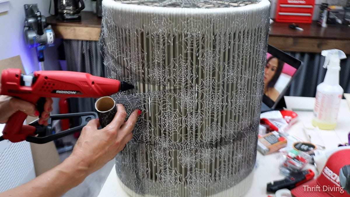 Wrapping ribbon around a table and securing with hot glue.