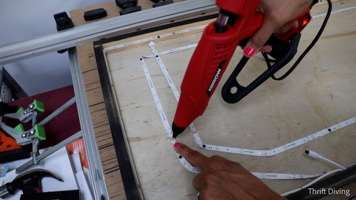 Hot gluing an LED light strip inside a custom light-up sign.