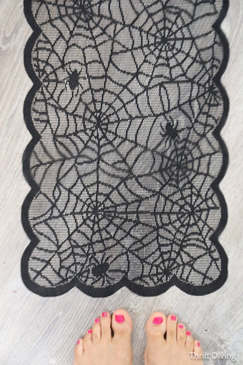 Black lace table runner with spider webs and spiders from The Dollar Tree.
