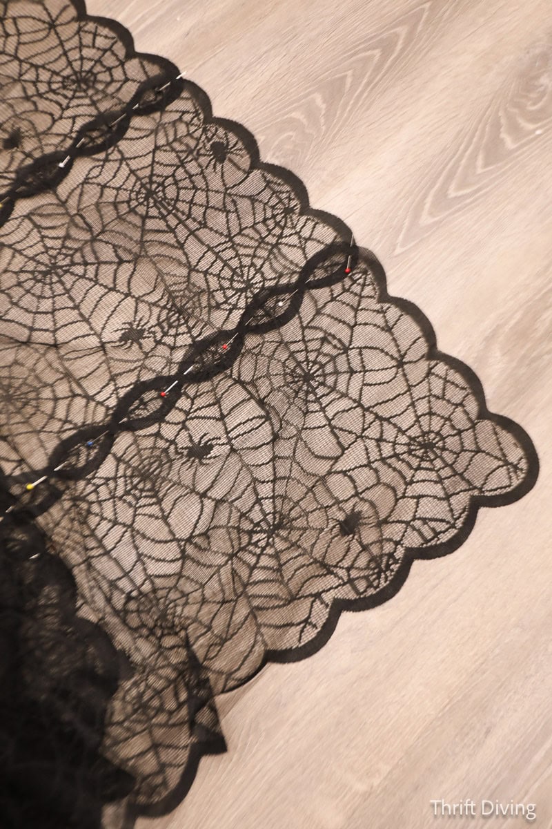 Dollar Tree lace Halloween table runner with scalloped edges and spider webs and spider designs, pinned together.