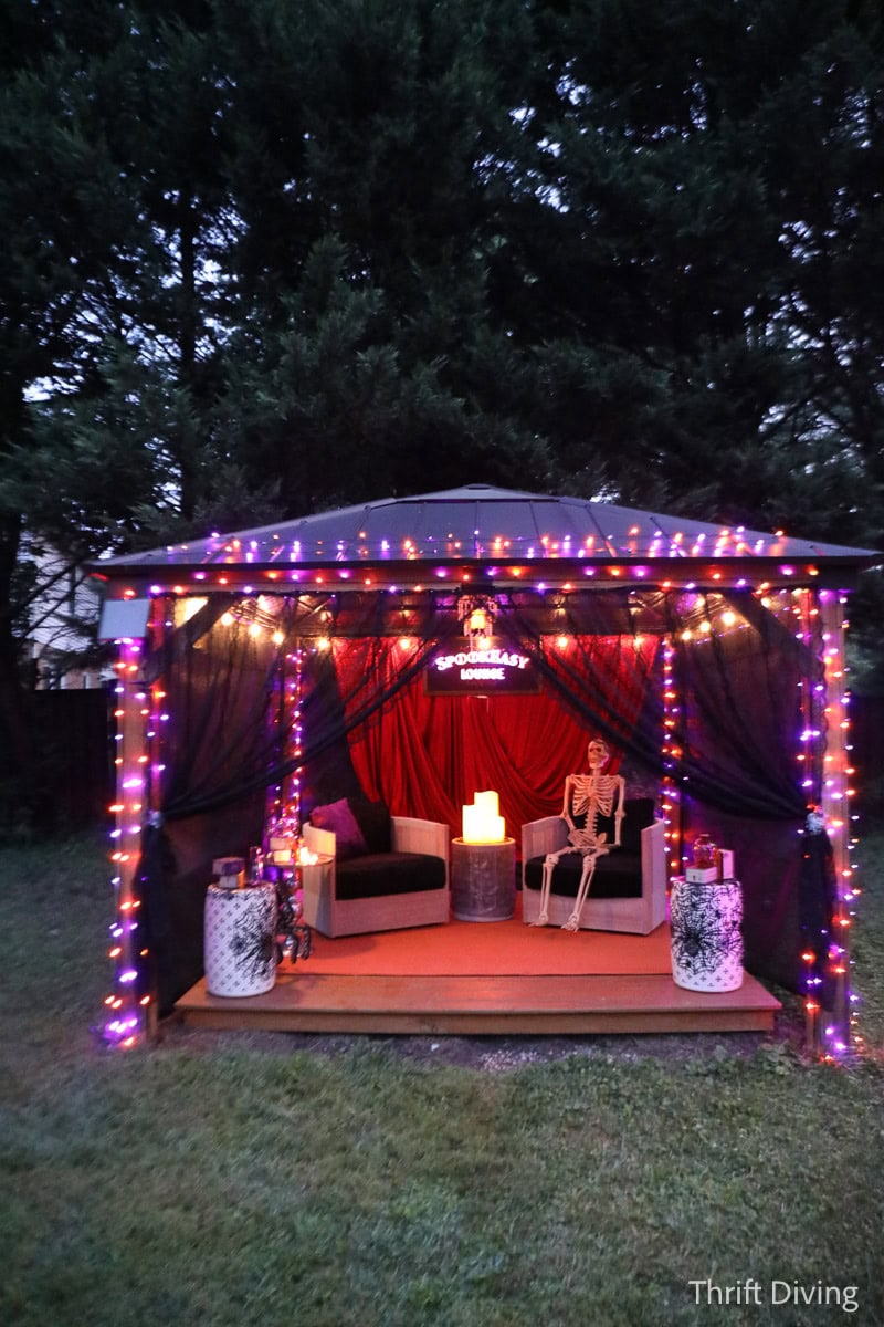 Cozy outdoor gazebo decorated for Halloween with lights, fabric, and a rich fabrics.